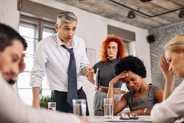 Foto ceo scontento che discute con il suo team e li rimprovera durante la riunione di lavoro in ufficio