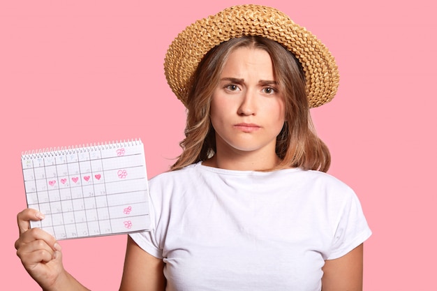 Displeased European woman in straw hat and casual t shirt