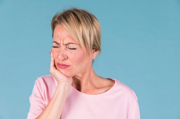 Displeased ill woman having toothache and touching his cheek