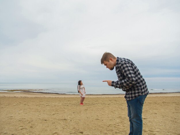 Displeased man scolding his wife on the beach. Conflict, quarrel and relationship problems.