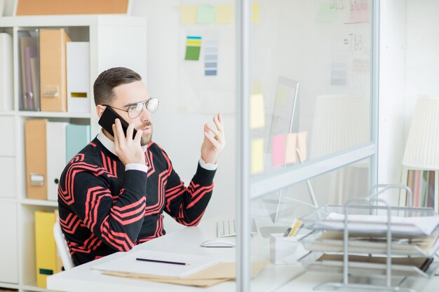 Displeased manager gesturing hand while talking by phone