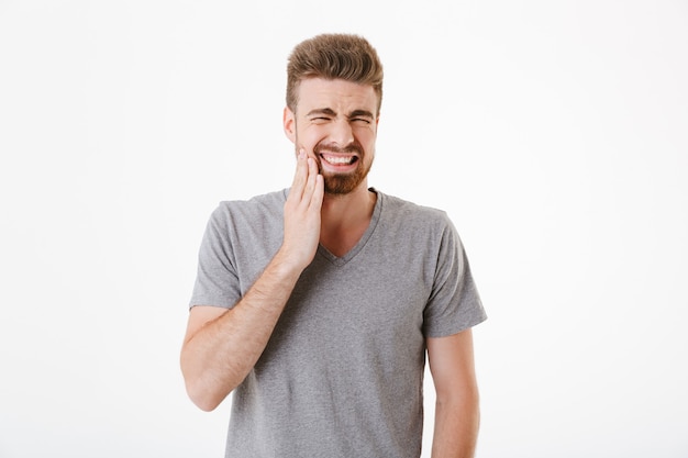 Displeased young man with toothache standing isolated