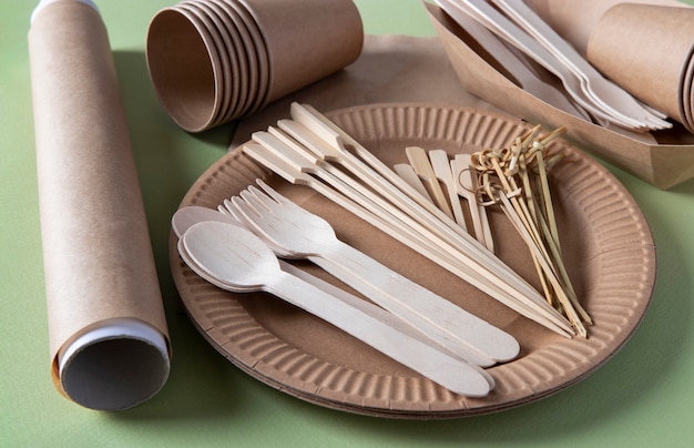 Disposable biodegradable tableware on craft paper plate - forks, spoons, glasses, bamboo skewers and parchment