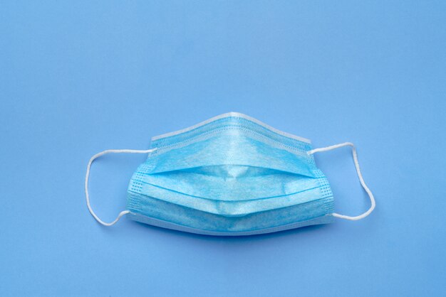 Disposable blue medical face mask on blue background.