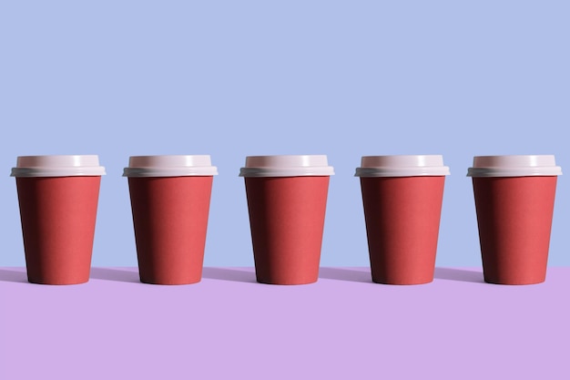 Disposable coffee cups organized in a row over blue background