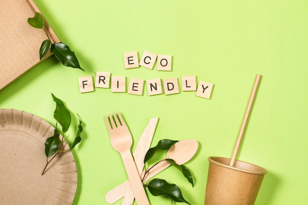 Disposable cup plate and wooden cutlery on a green background