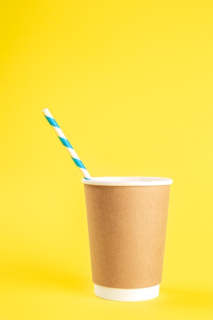 Photo disposable cup with a straw on a yellow background isolated
