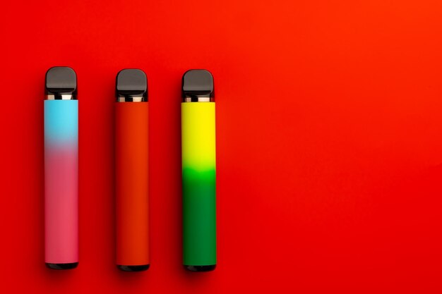 Disposable electronic cigarettes on red background close up