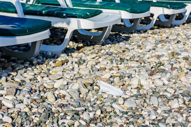 Una maschera usa e getta gettata sul sassolino in spiaggia