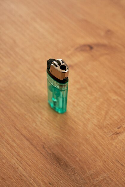 Disposable green lighter on a wooden table.