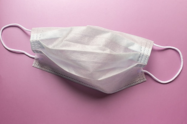 disposable medical mask on a light purple background.