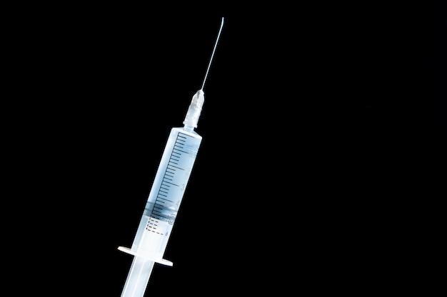 Disposable medical syringe with liquid on black