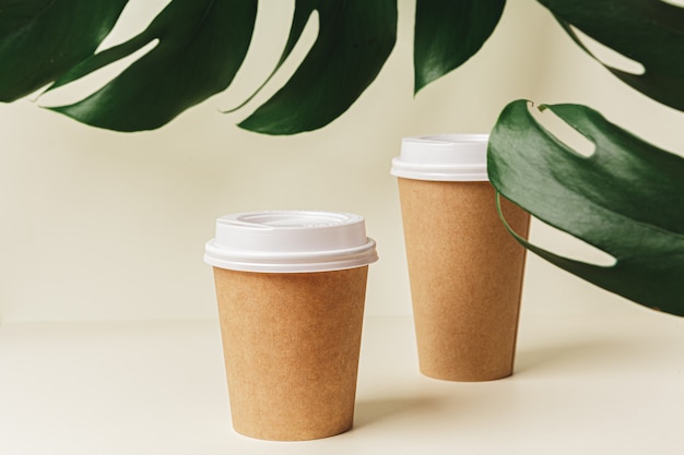 Одноразовые бумажные чашки кофе и зеленых листьев. Экологическая концепция