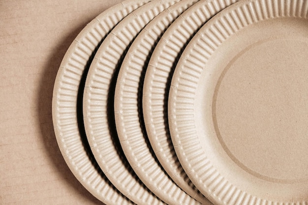 Одноразовые бумажные тарелки на фоне крафт-бумаги Экологичная одноразовая посуда