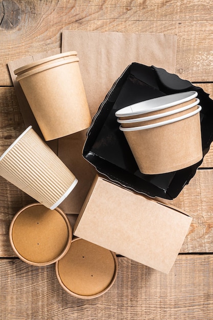 Disposable paper tableware Eco friendly Recycling set of paper cups dishes bag fast food containers and cutlery Wooden background Top view Copy space