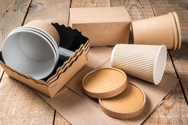 Disposable paper tableware Eco friendly Recycling set of paper cups dishes bag fast food containers and cutlery Wooden background Top view Copy space