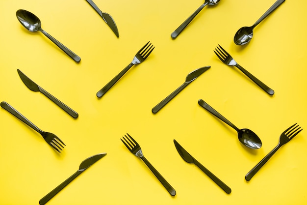 Disposable picnic black knife and forks on yellow. 