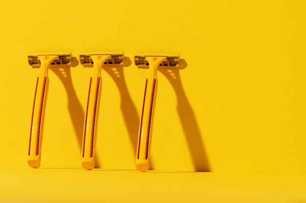 Disposable razors on yellow background, studio shot