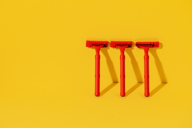 Disposable razors on yellow background, studio shot