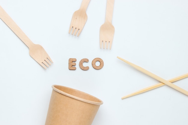 天然素材の使い捨て食器。環境にやさしいコンセプト。木製のフォーク、空のクラフトコーヒーカップ、白い背景の上の箸。