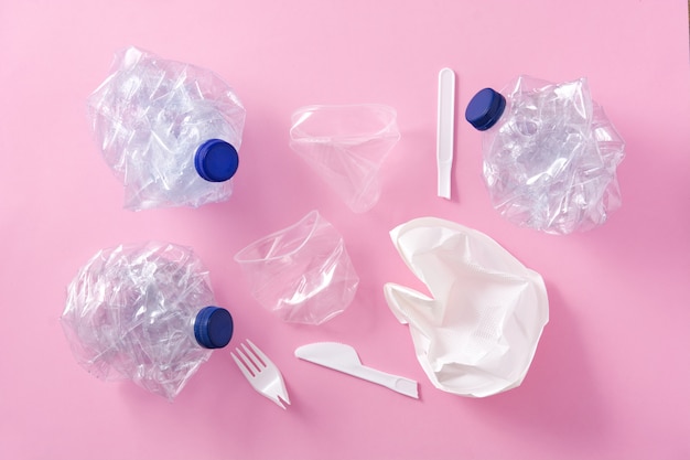 Disposable waste plastics on pink, top view