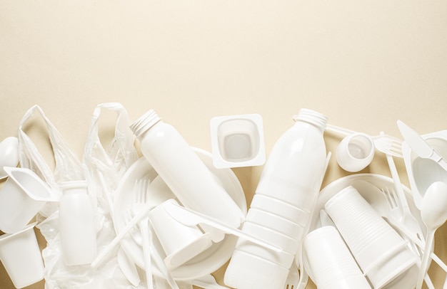 ベージュの背景に使い捨ての白いプラスチック製食器自然汚染の概念コピースペース