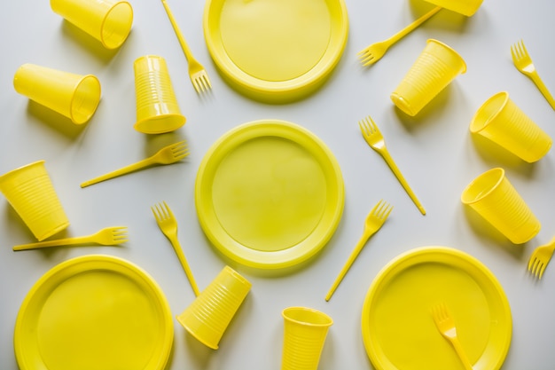 Photo disposable yellow picnic utensils on grey.