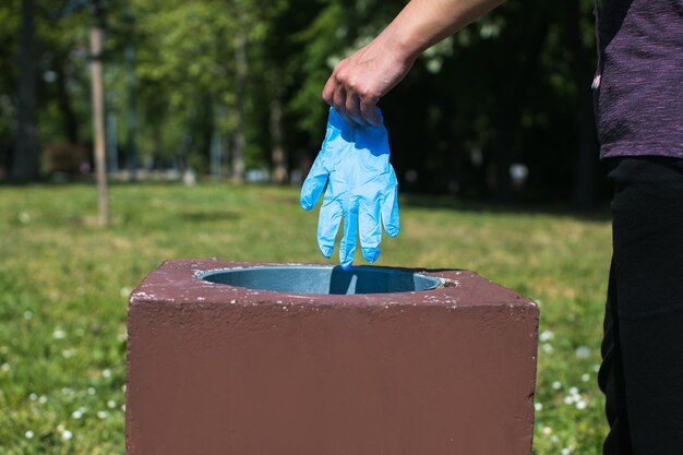 Photo disposing of protective glove in public park bin