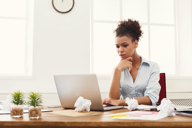 사무실에서 노트북 작업을 하는 불만족스러운 아프리카계 미국인 비즈니스 여성. 그녀의 작업 장소에 앉아있는 동안 컴퓨터에 뭔가를 입력하는 사업가, 공간 복사