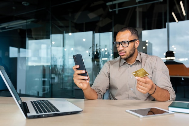 Dissatisfied and angry businessman in office trying to make purchase in online store hispanic man