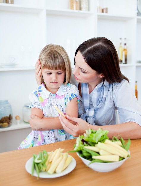 彼女の母親と野菜を食べるブロンドの女の子不満