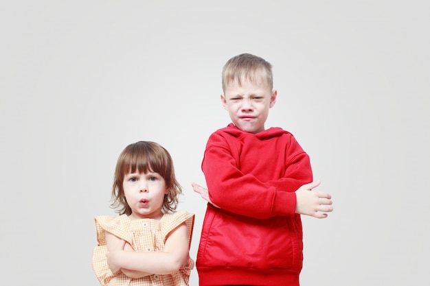 Dissatisfied children on gray wall. Brother and sister are annoyed, angry. Quarrel of children. Children's stress in the conditions of self-isolation krantin.