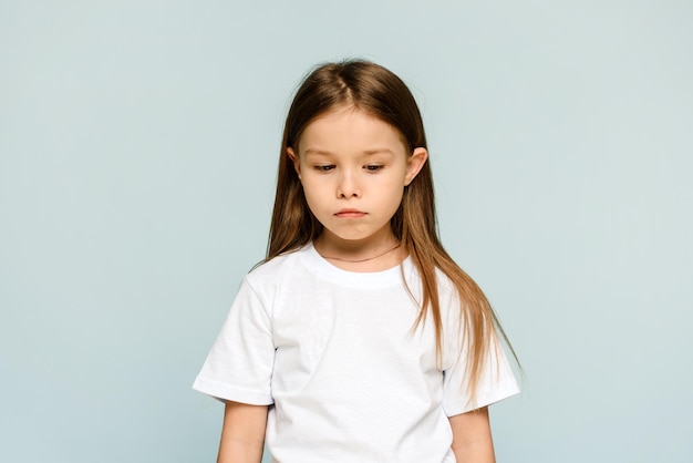 Dissatisfied little girl is offended on a blue background with copy space