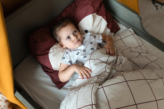 A dissatisfied little girl lies in bed and does not want to sleep