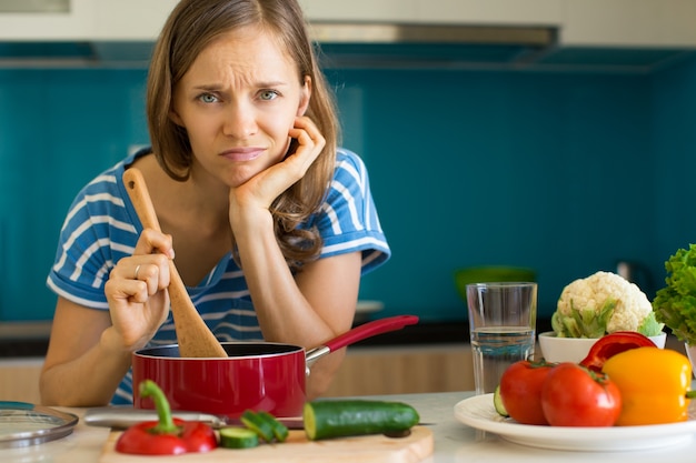 Foto donna insoddisfatta che cucina piatto in casseruola