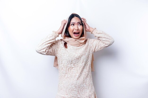 A dissatisfied young Asian Muslim woman looks at the camera posing on a white background disgruntled girl with irritated face expressions show negative attitude