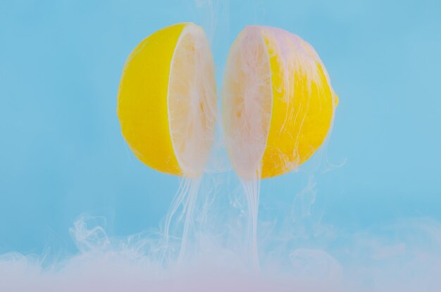 Dissolving pink poster color in water drop between two slice lemons for summer  concept