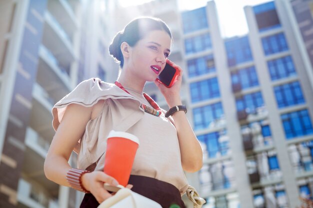 Distance communication. Pleasant young woman making a call while going from the office