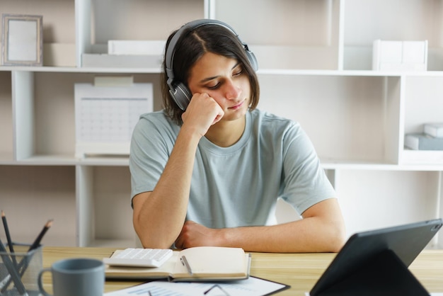 Distance education concept Teen boy sit to contemplate while listening lecture online on tablet