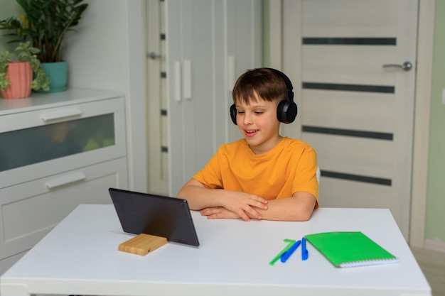 Distance education at home during quarantine child elementary\
school boy doing homework with a tablet