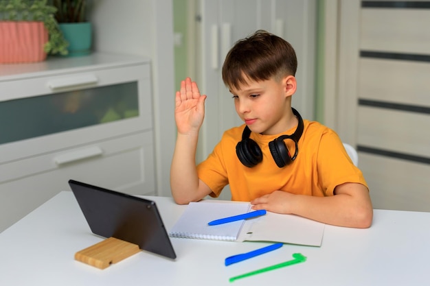 Distance education at home during quarantine child elementary school boy doing homework with a tablet