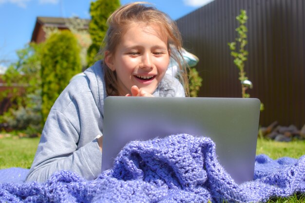 Distance learning. A girl is studying remotely outdoor in park. Home education.