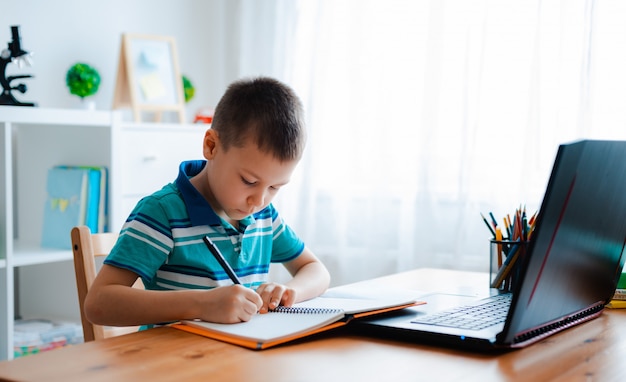 Distance learning online education. A schoolboy boy studies at home and does school homework. A home distance learning