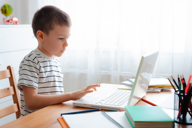 Distance learning online education. A schoolboy boy studies at home and does school homework. A home distance learning