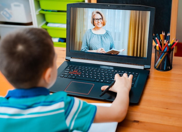 Distance learning online education A schoolboy boy studies at home and does school homework A home distance learning