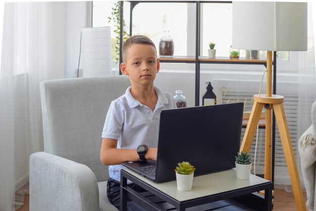 Distance learning online education A schoolboy boy studies at home and does school homework