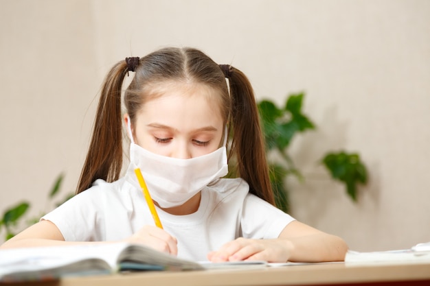 Distance learning online education. schoolgirl in medical mask studying at home,