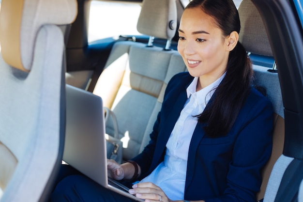 Distance work. Joyful nice businesswoman holding her laptop while working from a distance