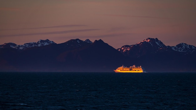 Photo distant cruise ship illuminated by setting sun off alaska coast