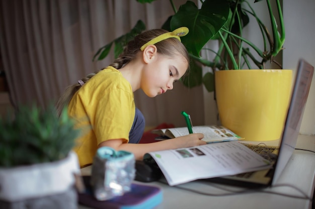 Distant education cute schoolchild studying homework during online lesson at home social distance